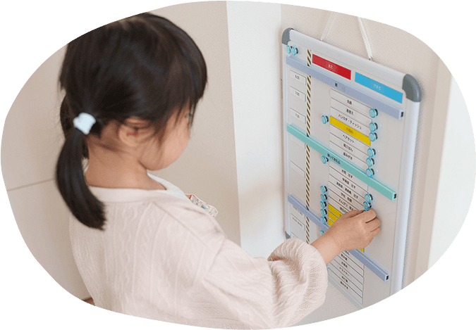 女の子がスケジュールボードのマグネットを触っている