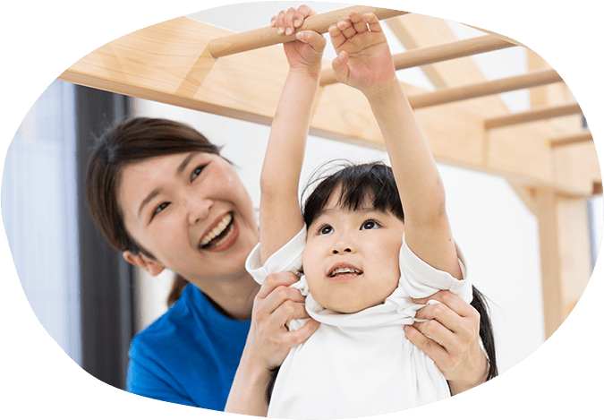 うんていをしている女の子とそれを支えるスタッフ